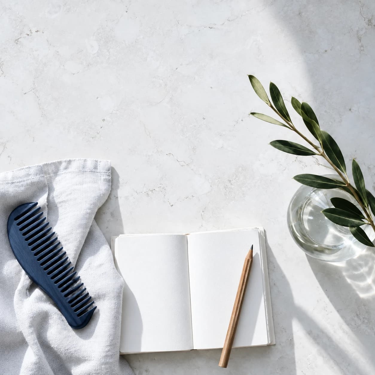 A navy comb, white linen and an open notebook in neutral daylight